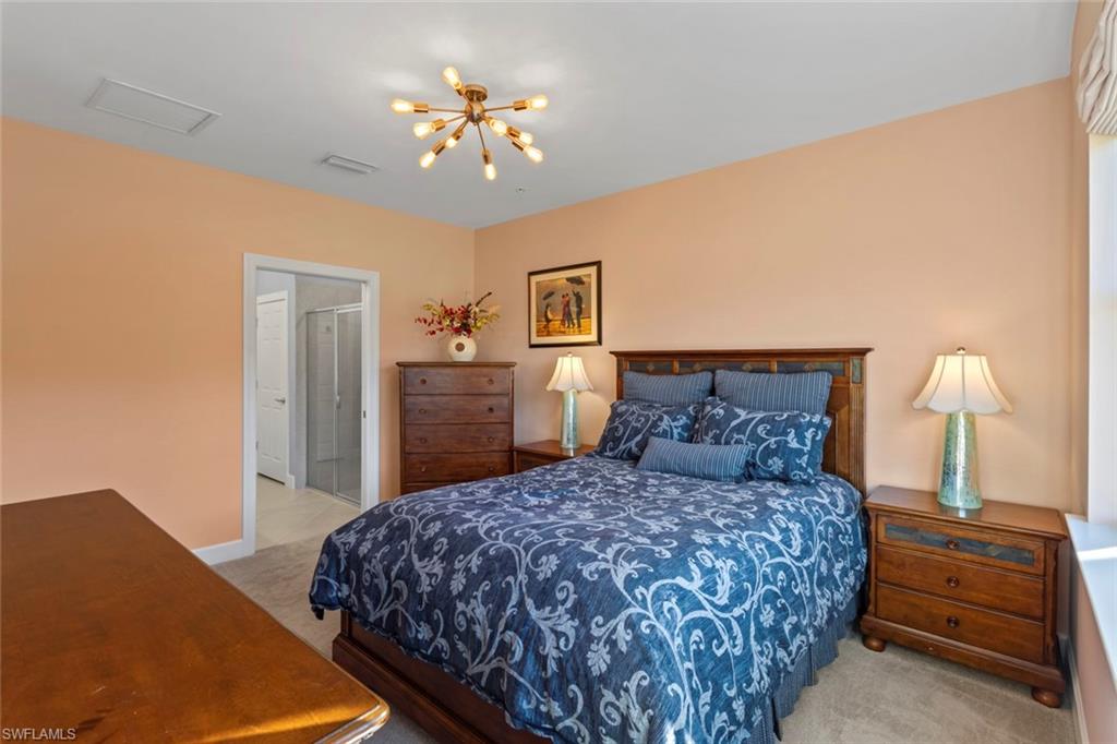 5701 Mayflower Way, Unit 1302 Ave Maria, FL 34142 - Photo 14 of 32 a bedroom with a large bed and a chandelier