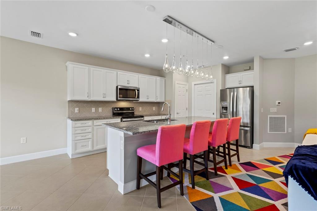 5701 Mayflower Way, Unit 1302 Ave Maria, FL 34142 - Photo 8 of 32 a kitchen with stainless steel appliances granite countertop a dining table chairs refrigerator and microwave
