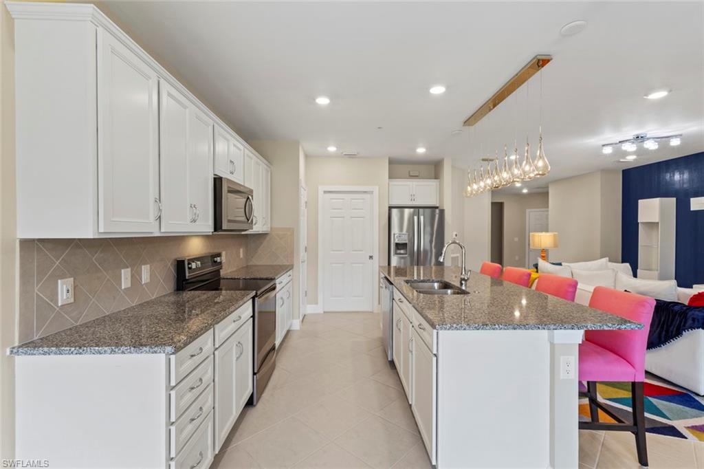 5701 Mayflower Way, Unit 1302 Ave Maria, FL 34142 - Photo 9 of 32 a kitchen with kitchen island granite countertop a sink and cabinets