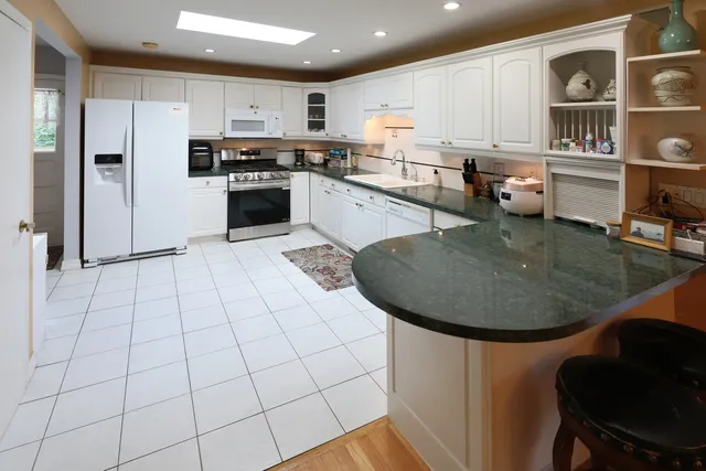 a kitchen with stainless steel appliances granite countertop a sink a stove a refrigerator cabinets and chairs