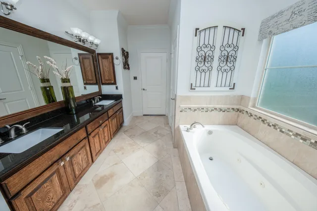a spacious bathroom with a tub sink and mirror