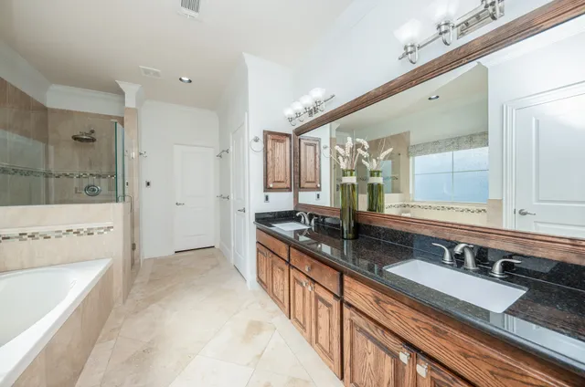 a large bathroom with a granite countertop double vanity sink a mirror and a bathtub