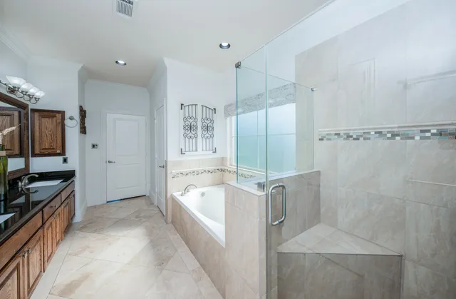 a spacious bathroom with a granite countertop sink a mirror a bathtub and shower