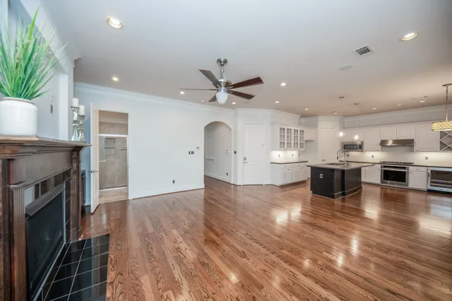 a view of an empty room with wooden floor and a ceiling fan