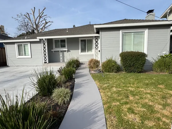 a front view of a house with a yard and potted plants