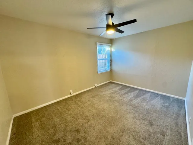 an empty room with a ceiling fan and a window