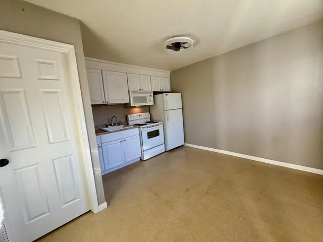 a kitchen with stainless steel appliances granite countertop a refrigerator a stove a sink and white cabinets