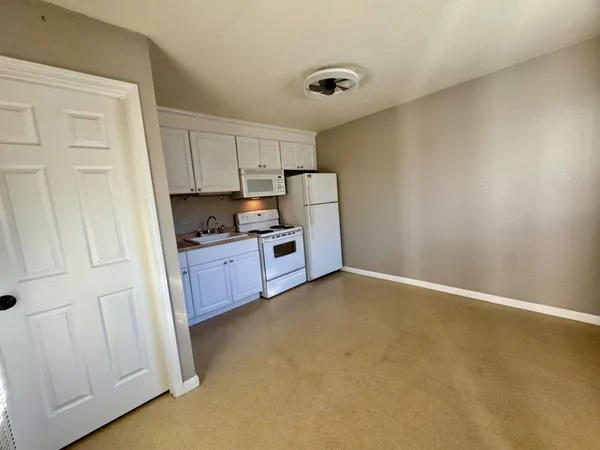 a kitchen with stainless steel appliances granite countertop a refrigerator a stove a sink and white cabinets