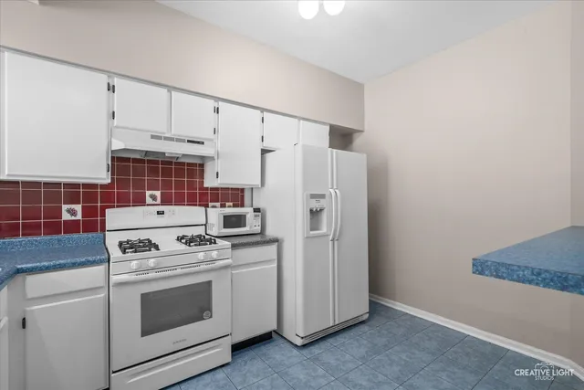 a kitchen with white cabinets and white appliances