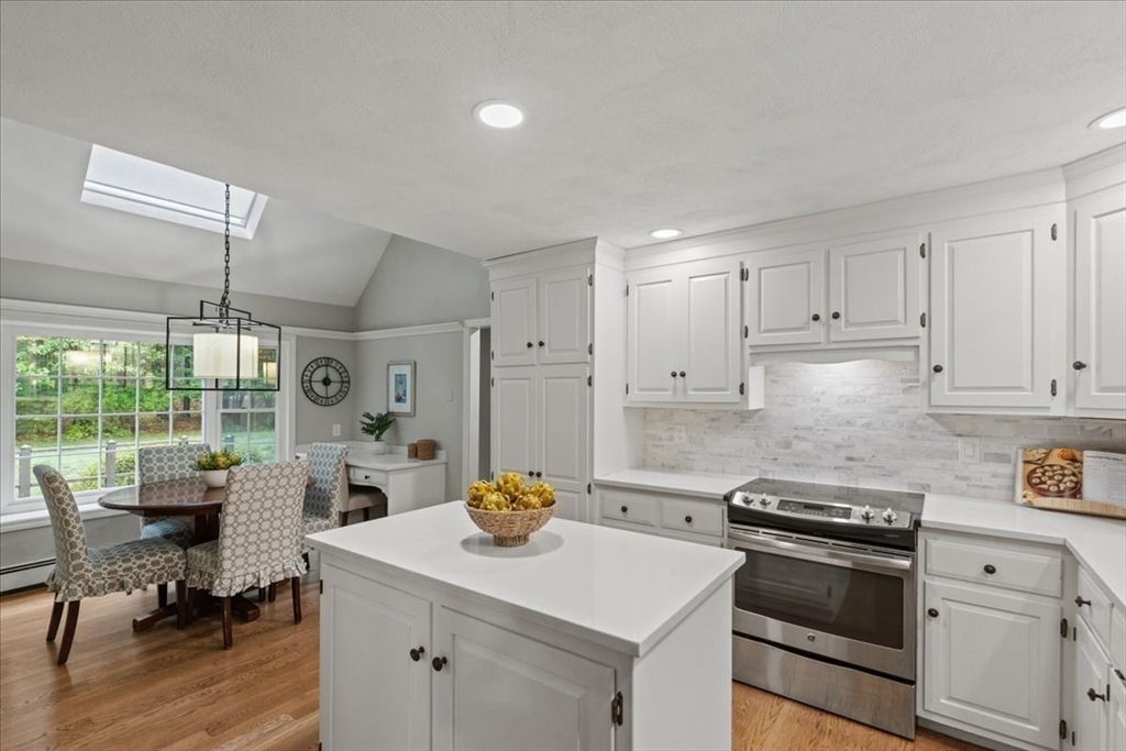 74 Granite Street Walpole, MA 02052 - Photo 10 of 40 a kitchen with a stove a refrigerator and a dining table with wooden floor