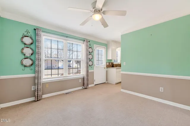 a view of an empty room with windows and chandelier fan