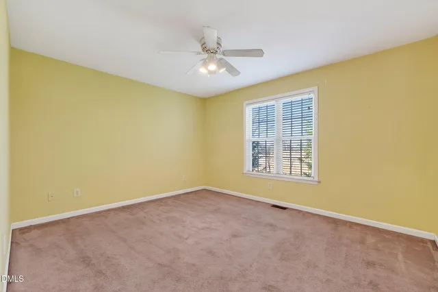 an empty room with a ceiling fan and a window