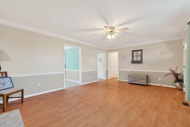 a view of an empty room with window and wooden floor