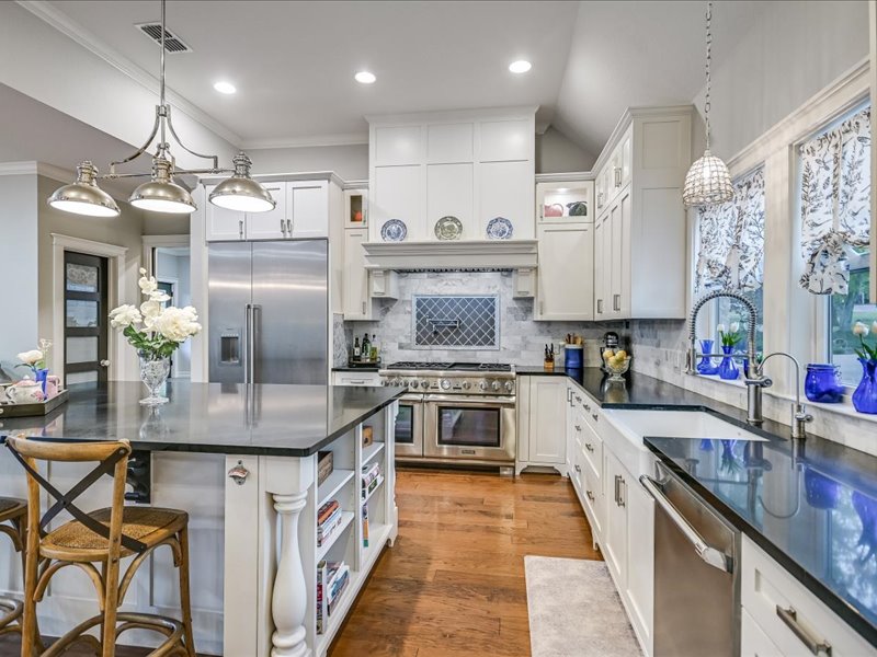 14036 Timberline Trail Austin, TX 78737 - Photo 7 of 40 Kitchen with decorative light fixtures, a breakfast bar, glass insert cabinets, open shelves, and white cabinetry