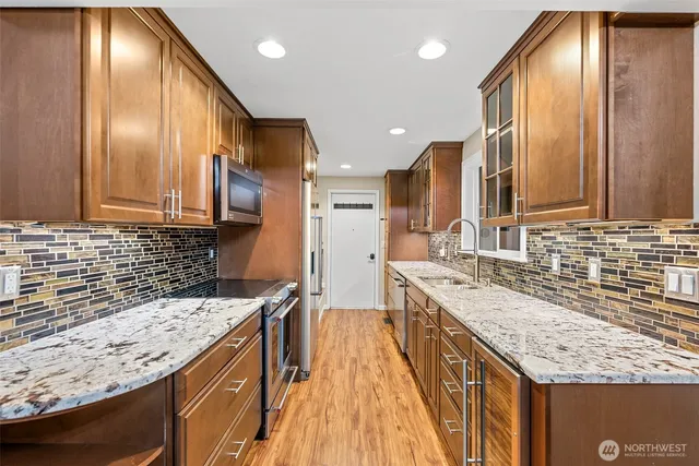 a kitchen with stainless steel appliances granite countertop refrigerator a sink and wooden cabinets