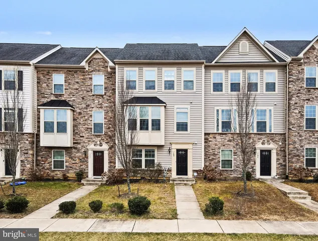 a front view of a residential houses with yard and parking
