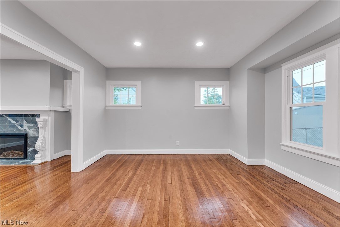 Wood floored spare room featuring a healthy amount of sunlight and a fireplace