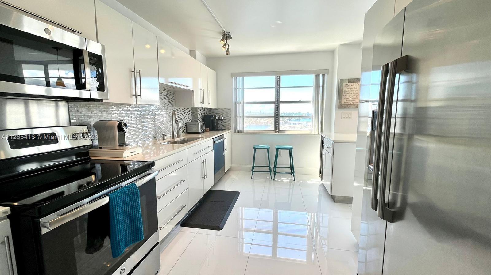 2851 Northeast 183rd Street, Unit 1816E Aventura, FL 33160 - Photo 9 of 29 a white kitchen with stainless steel appliances a stove a sink and a refrigerator