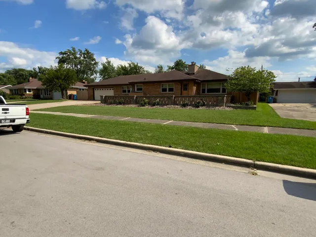 a view of a big house next to a yard with big trees