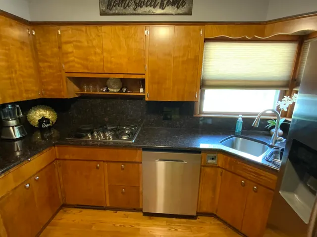 a kitchen with stainless steel appliances granite countertop a refrigerator a sink and wooden cabinets