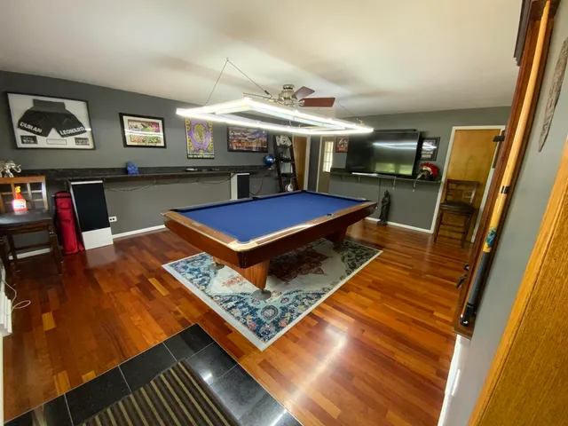 a kitchen with stainless steel appliances granite countertop a stove a refrigerator a sink a dining table and chairs with wooden floor