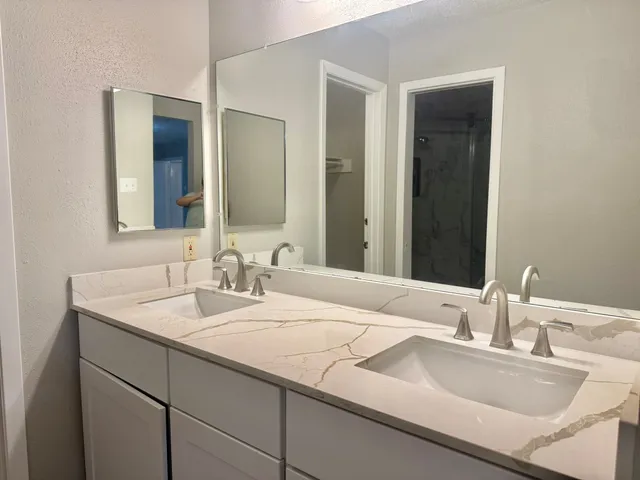 a bathroom with double sink and a mirror