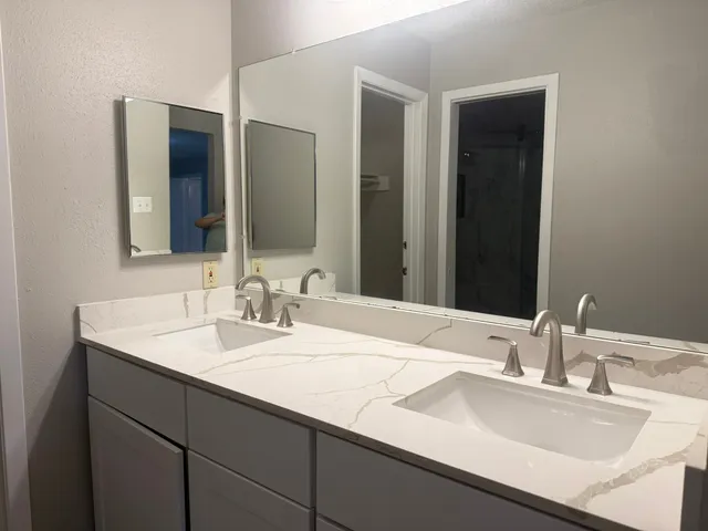 a bathroom with double sink and a mirror