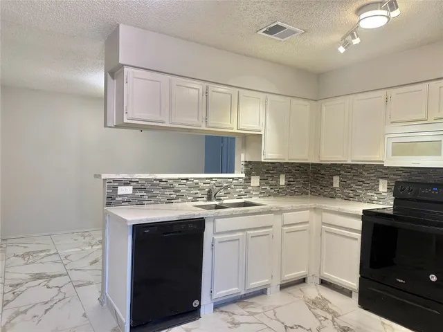a kitchen with granite countertop a sink stove and cabinets