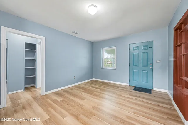 a view of empty room with window and wooden floor