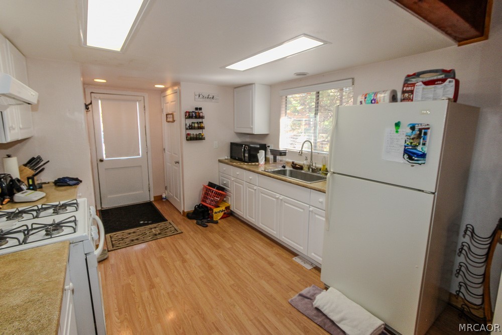 533 Victoria Lane Sugarloaf, CA 92386 - Photo 13 of 36 a kitchen with a refrigerator a stove a wooden floor and a sink