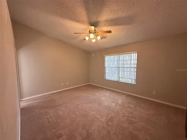 an empty room with a window and a ceiling fan