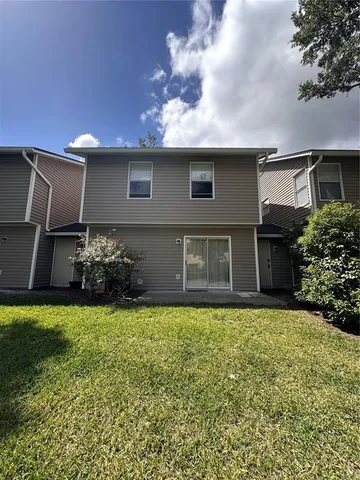 a view of a house with a yard and a large tree
