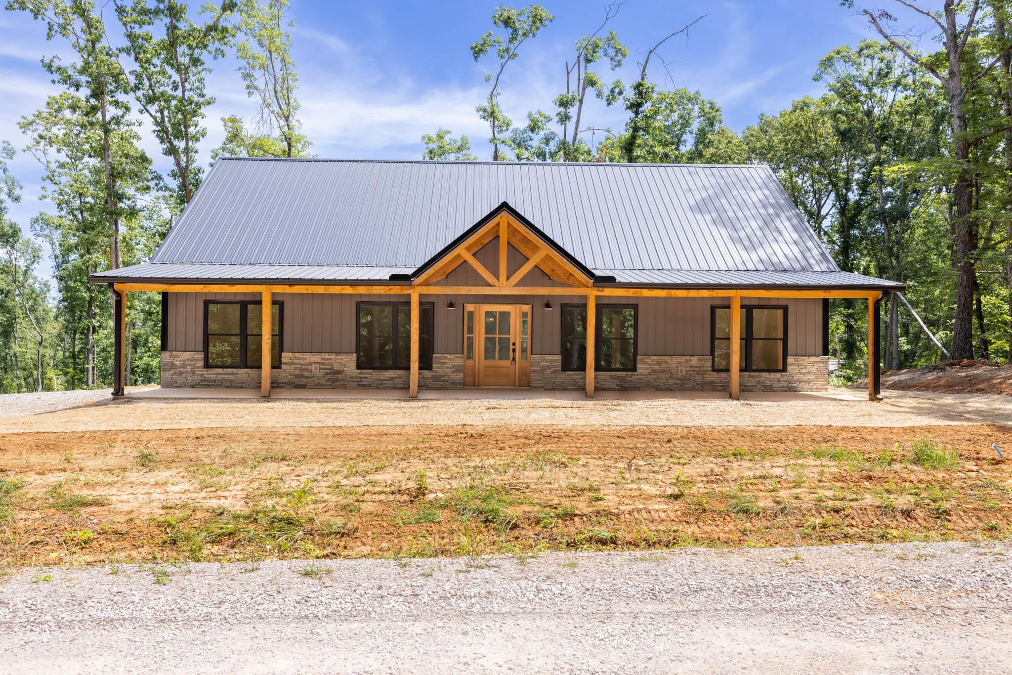 37 William Teague Lane Ramer, TN 38367 - Photo 2 of 39 Modern cabin exterior featuring a metal roof, stone veneer siding, and a covered porch with exposed wood beams