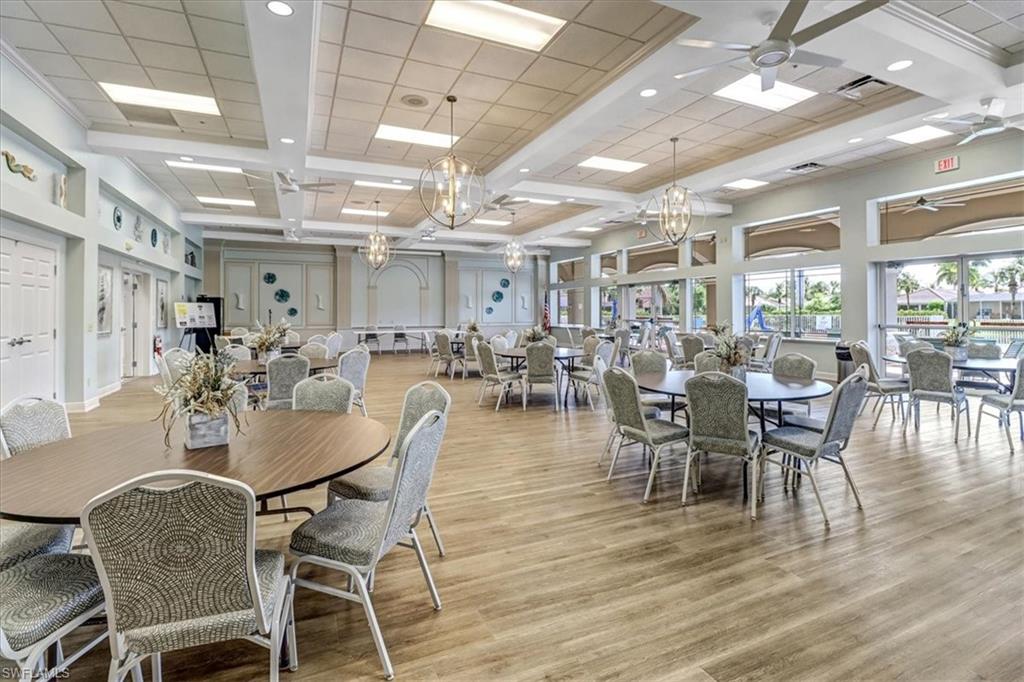 14130 Winchester Court, Unit 1503 Naples, FL 34114 - Photo 31 of 39 Dining space with a high ceiling, light wood-type flooring, and ceiling fan with notable chandelier