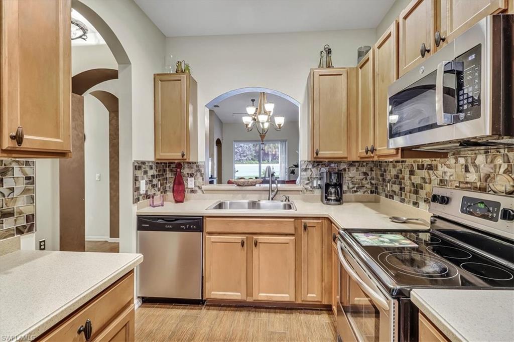 14130 Winchester Court, Unit 1503 Naples, FL 34114 - Photo 4 of 39 Kitchen featuring backsplash, a notable chandelier, light wood-type flooring, appliances with stainless steel finishes, and sink