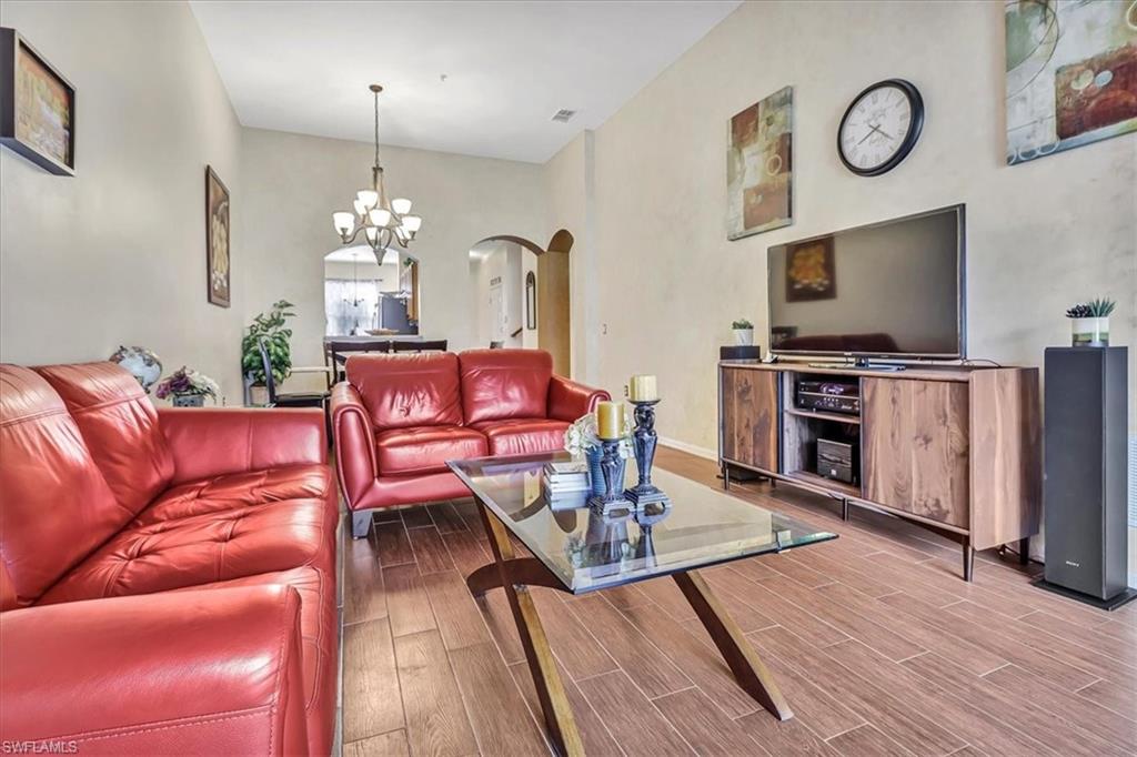 14130 Winchester Court, Unit 1503 Naples, FL 34114 - Photo 8 of 39 Living room with a notable chandelier and hardwood / wood-style flooring