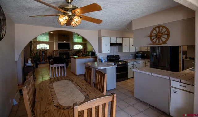 a kitchen with stainless steel appliances kitchen island granite countertop a stove a sink a refrigerator and a dining table