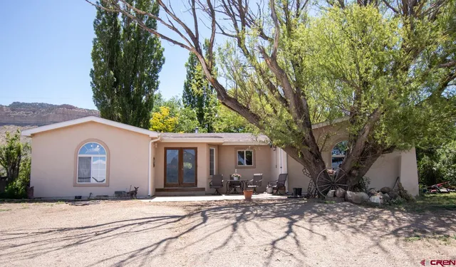 a view of a white house with a yard and large tree
