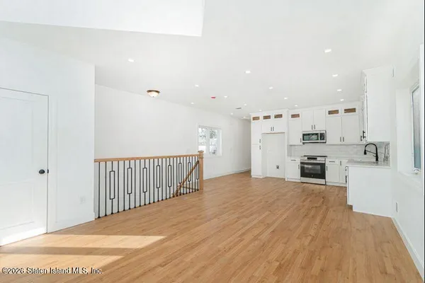 a view of a kitchen with a sink and dishwasher a refrigerator with wooden floor
