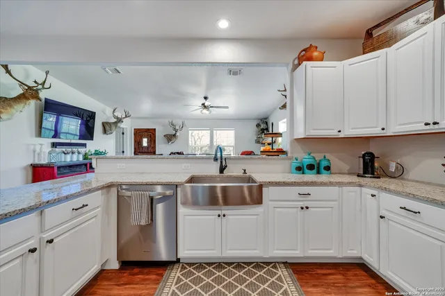 a kitchen with stainless steel appliances granite countertop a refrigerator a stove top oven a sink dishwasher and white cabinets with wooden floor