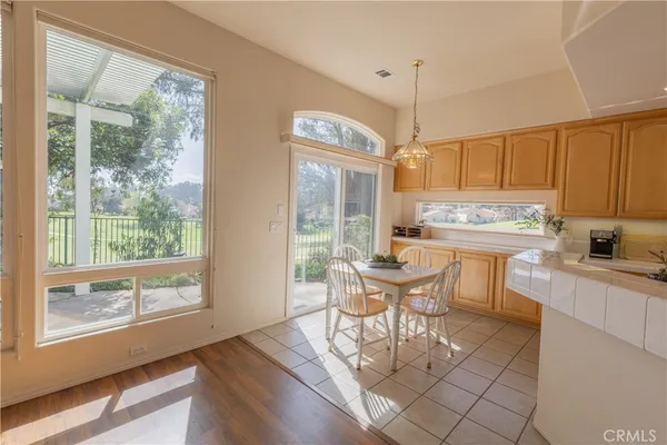 a kitchen with stainless steel appliances a dining table chairs and large windows