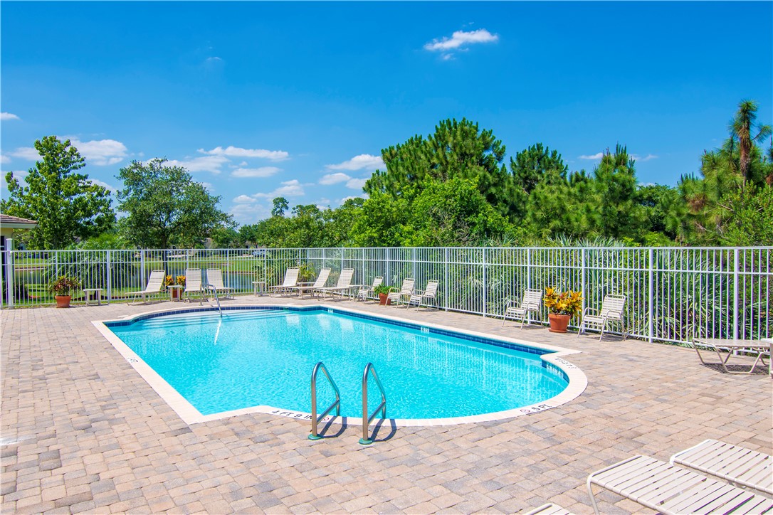 2541 Stockbridge Square Southwest Vero Beach, FL 32962 - Photo 28 of 33 a view of a swimming pool with a lake and trees in the background