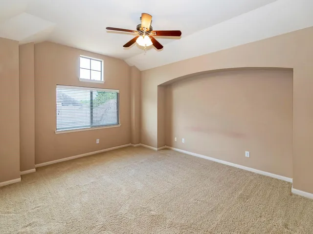 an empty room with windows and fan