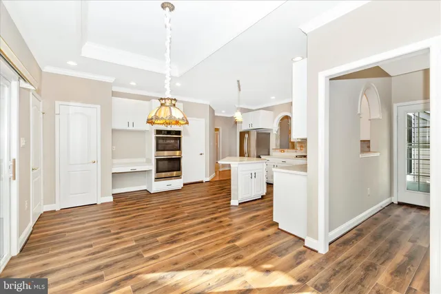 an empty room with wooden floor chandelier and windows