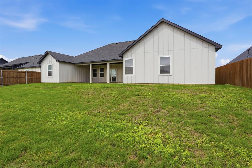 532 Highview Court Godley, TX 76044 - Photo 37 of 39 Expansive backyard featuring a lush green lawn, full privacy fencing, and a covered patio area with a sliding glass door