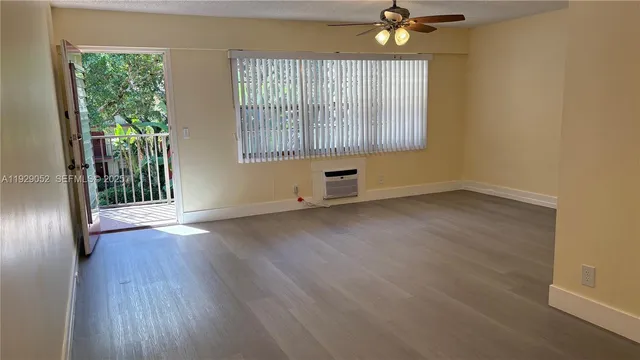 a view of an empty room with a window and wooden floor