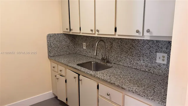a kitchen with granite countertop a sink and cabinets