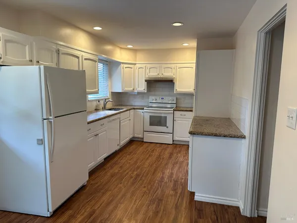 a kitchen with stainless steel appliances granite countertop a refrigerator a sink dishwasher and a stove with wooden floor