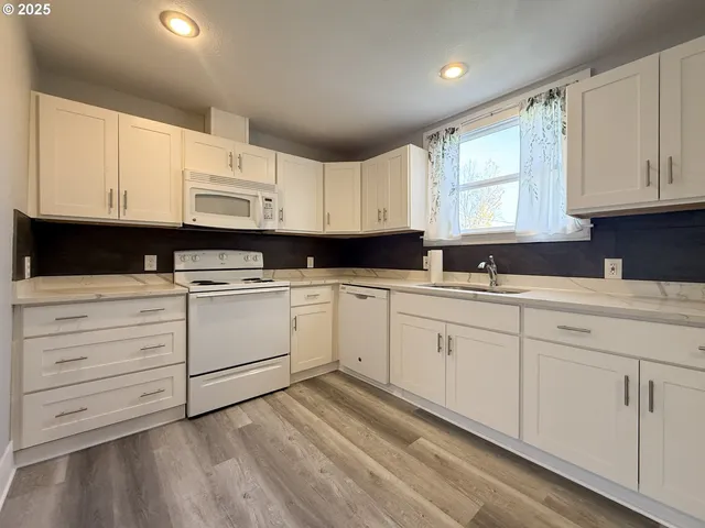 a kitchen with granite countertop white cabinets white stainless steel appliances and sink