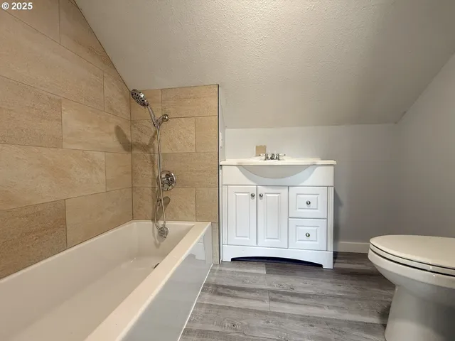 a bathroom with a granite countertop bathtub shower sink and toilet